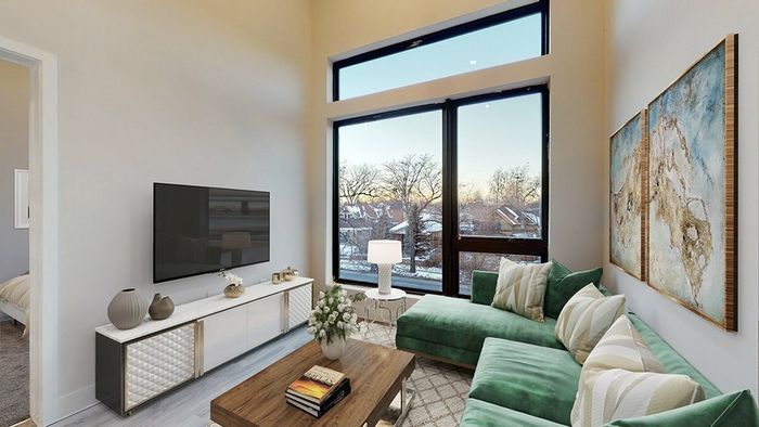 Living room in Denver apartments featuring high ceilings, large windows, a sectional couch, and wood-style flooring, perfect for urban living near Jefferson Park.