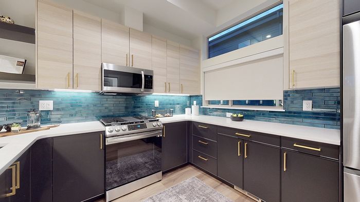 Kitchen with modern finishes including two-tone kitchen cabinets, gas cooking, stainless steel appliances, colorful backsplash, and wood-style flooring