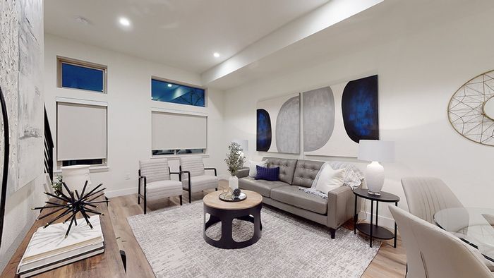 Living room with comfortable seating and large windows with roller shades
