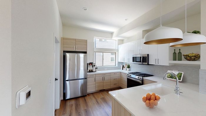 Bright kitchen with French door refrigerator, gas cooking, large windows, wood-style flooring, and pendant lighting