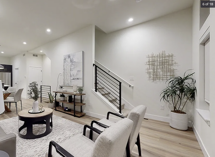 Modern living room with sleek staircase, elegant decor, and lush indoor plants, creating a bright and inviting space.