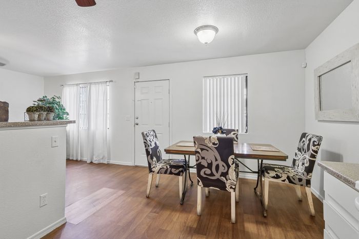 Inviting dining area with elegant patterned chairs, natural light, and warm wood flooring in a modern apartment.