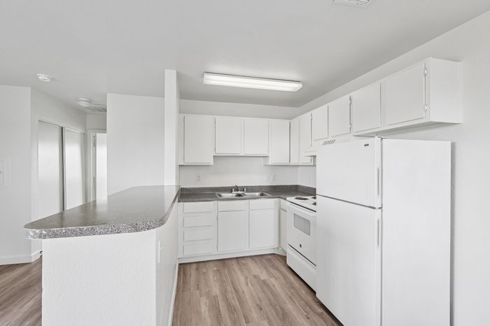 Bright, modern kitchen with a sleek white design, featuring ample cabinetry, a spacious countertop, and elegant flooring.