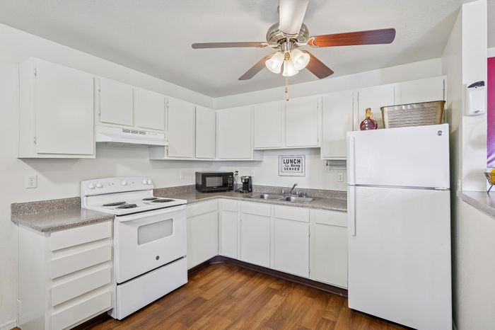 Bright, well-appointed kitchen with modern appliances, gleaming white cabinets, and stylish wood flooring, perfect for culinary adventures.