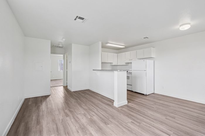 Bright and modern open-plan kitchen and living space with sleek white cabinetry and elegant wood flooring.