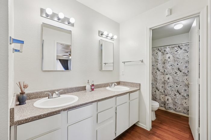 Elegant bathroom with dual sinks and a floral-patterned shower curtain, featuring modern lighting and ample counter space.
