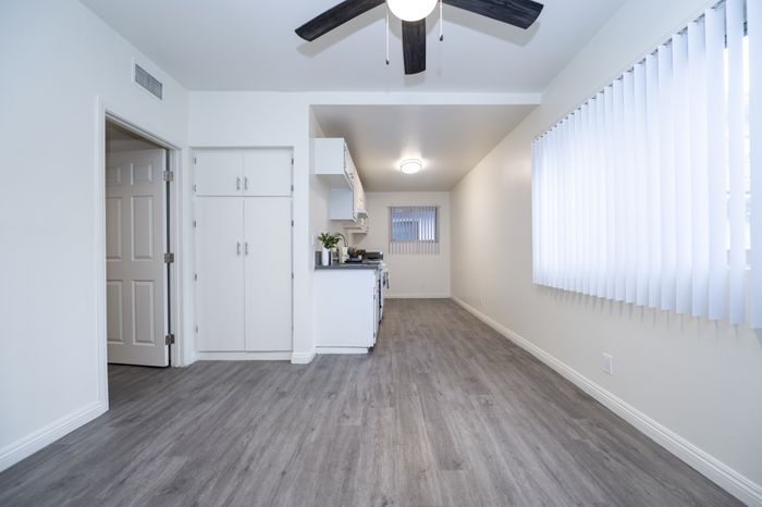Bright and modern kitchen with sleek white cabinets, gray flooring, and large windows offering abundant natural light.