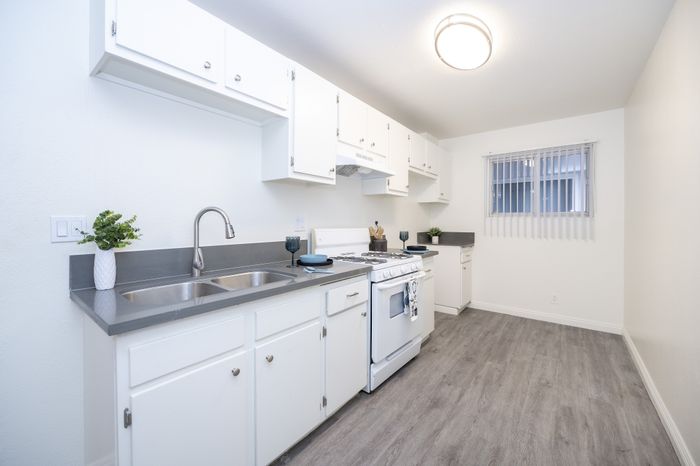 Bright and modern kitchen with sleek grey countertops, white cabinetry, and stylish flooring, bathed in natural light.