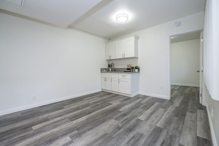 Modern apartment interior featuring sleek white cabinetry, stylish light fixture, and elegant wood flooring.
