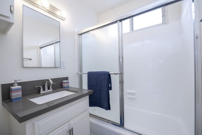 Modern bathroom with sleek vanity, elegant mirror, and a stylish glass-enclosed shower with natural light.