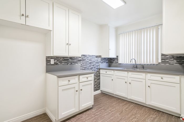Bright and modern kitchen with sleek white cabinets, elegant gray countertops, and stylish backsplash.