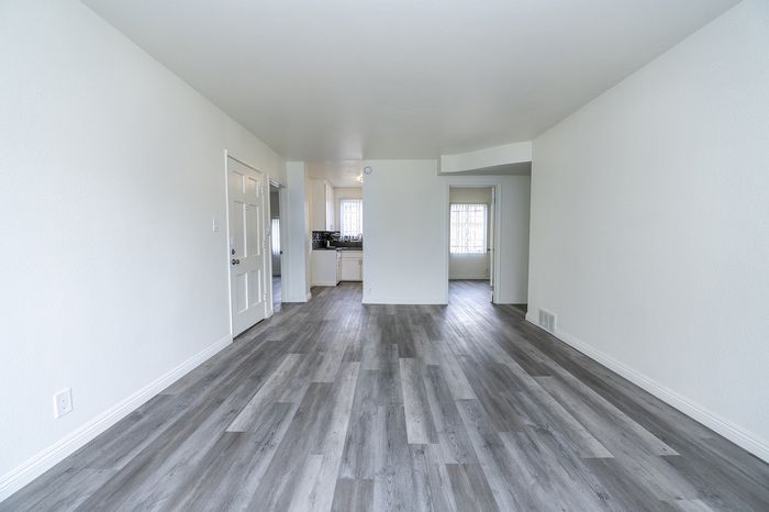 Bright and spacious open-plan living area with modern flooring and natural light flowing into the kitchen. Ideal for contemporary living.