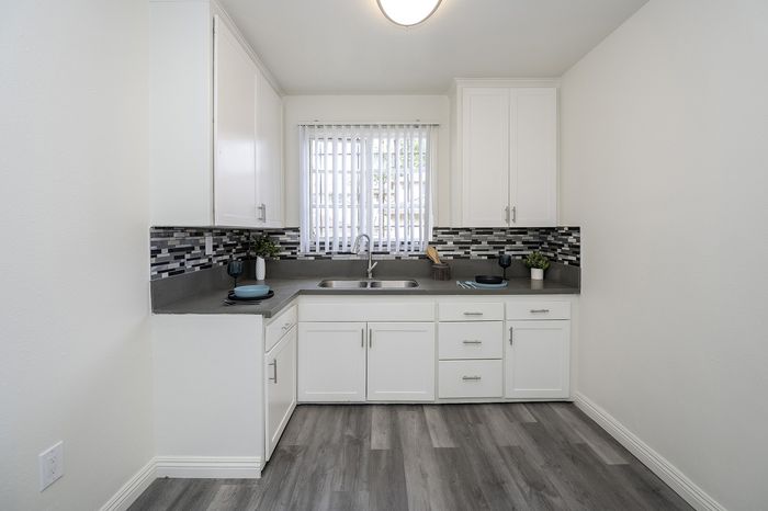 Bright, modern kitchen with elegant white cabinetry, sleek grey counters, and stylish geometric backsplash, ideal for culinary creativity.