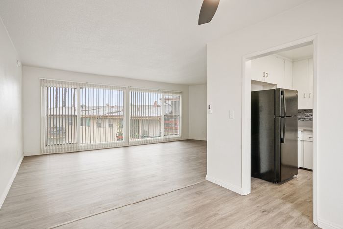 Bright and airy living space featuring large windows with vertical blinds, open floor plan, and inviting kitchen area.