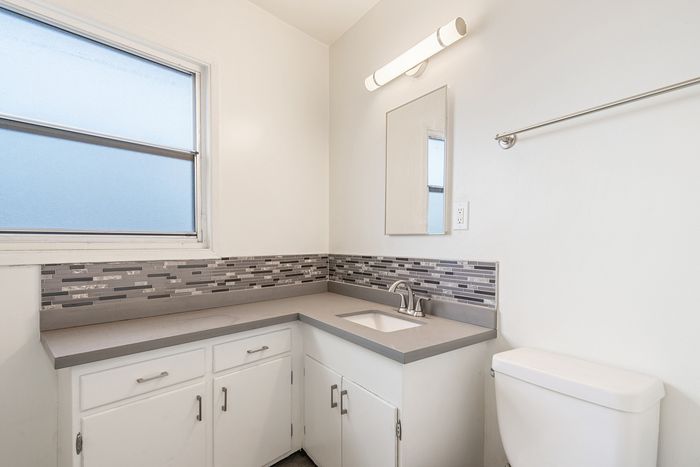 Bright bathroom with modern fixtures, elegant tiled backsplash, and abundant natural light.