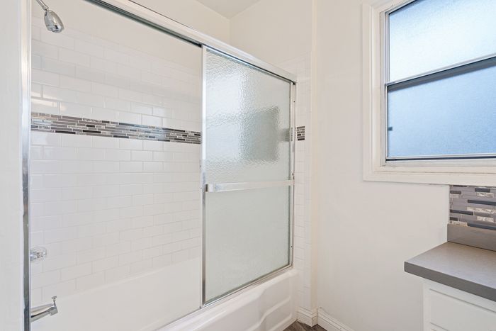 Bright and modern bathroom with elegant subway tiles and glass shower enclosure, featuring sleek countertop design.
