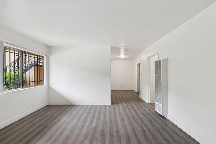 Bright and airy apartment interior with modern wood flooring and large window view.