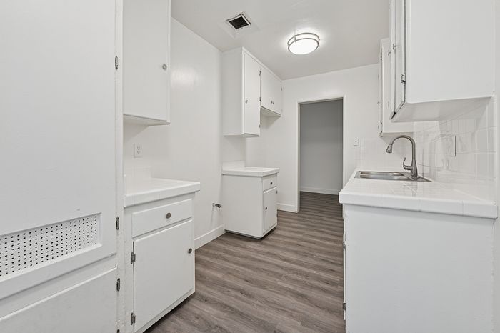 Charming kitchen with sleek white cabinets and modern lighting, ideal for culinary creativity.