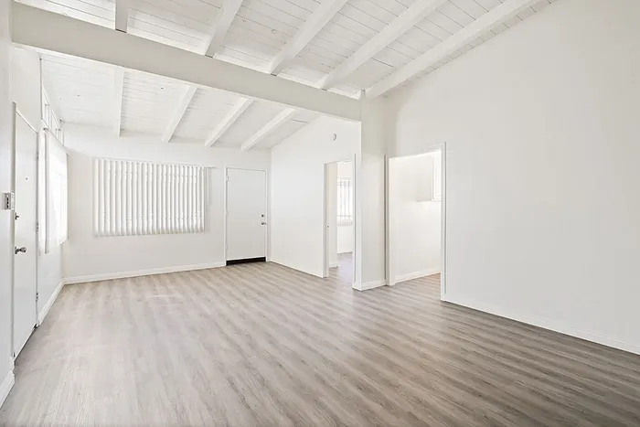 Bright and airy living space with vaulted ceilings, elegant wood flooring, and ample natural light.