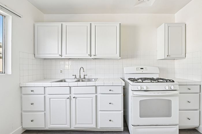 Bright and inviting kitchen with pristine white cabinets, modern appliances, and sleek tile countertops.
