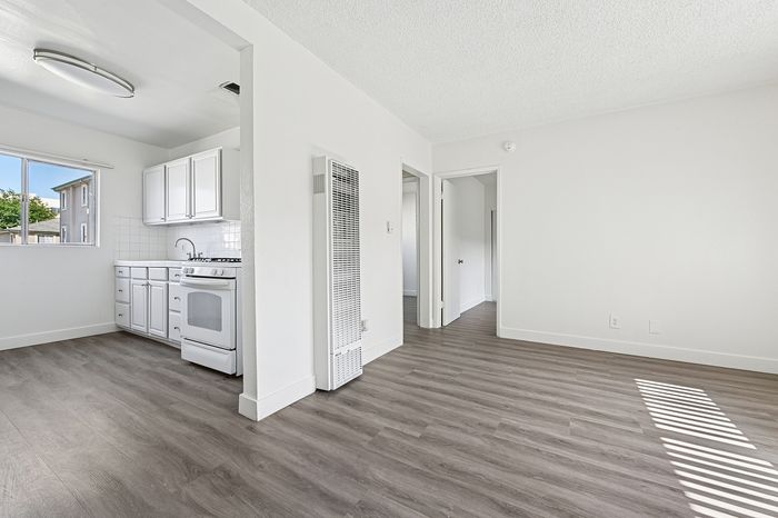 Bright and airy apartment featuring an open kitchen with white cabinets and modern flooring.