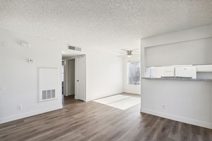 Bright and inviting living space with modern hardwood floors, an open kitchen, and ample natural light streaming through large windows.