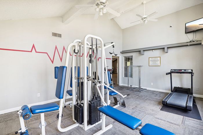 Modern fitness center with state-of-the-art exercise equipment, featuring a treadmill and multi-station gym machine in a bright, airy space.