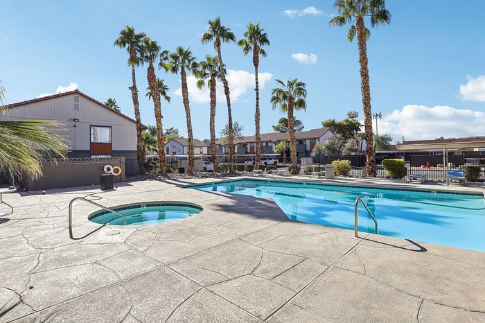 Inviting outdoor pool and spa area surrounded by palm trees, perfect for relaxation in a sunny residential community.