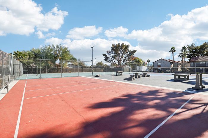 Vibrant outdoor sports courts featuring a tennis and basketball court surrounded by lush greenery and scenic views, perfect for active living.