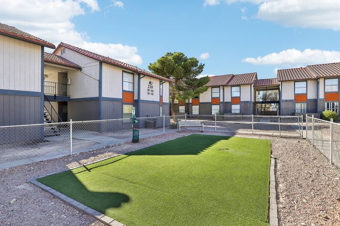 Charming apartment complex with tiled roofs, communal green space, and inviting outdoor seating area.