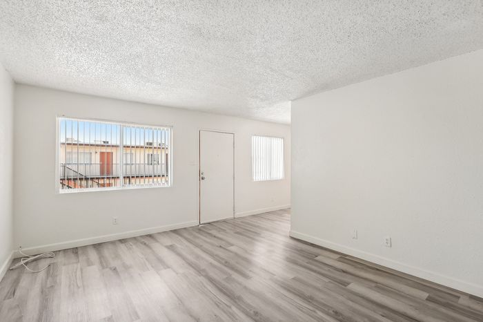 Bright and airy living space with modern hardwood flooring, enhanced by natural light through large windows.