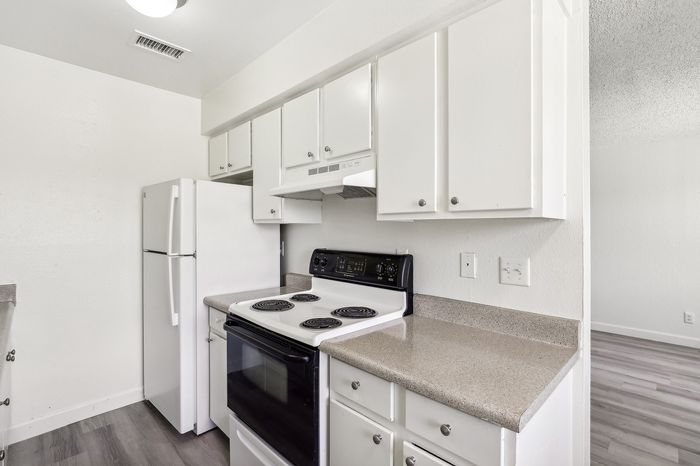 Modern kitchen with sleek white cabinetry, electric stove, and spacious countertops in a bright, inviting space.