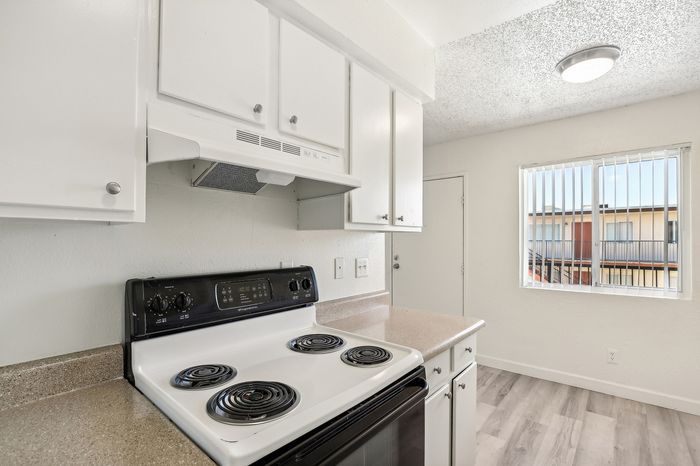 Bright kitchen with modern white cabinetry, electric stove, and a large window for natural light.
