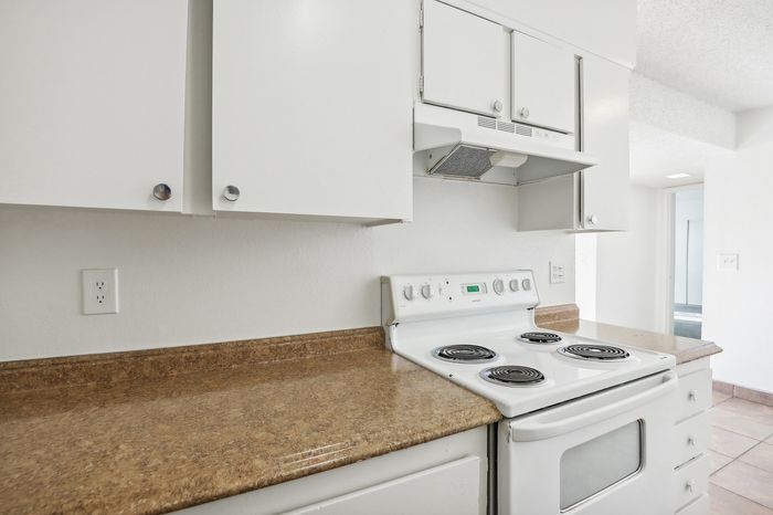 Bright kitchen with white cabinets, modern appliances, and a spacious countertop, perfect for culinary exploration.
