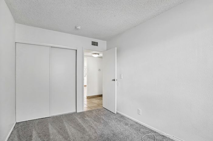 Bright, cozy bedroom with modern sliding closet doors and soft carpet flooring, offering a tranquil retreat.