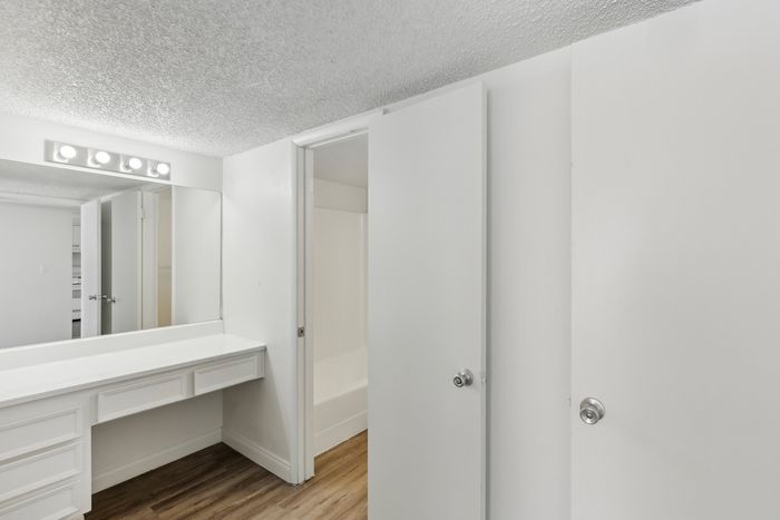Elegant bathroom with sleek white cabinets, modern lighting, and wood flooring for a sophisticated look.