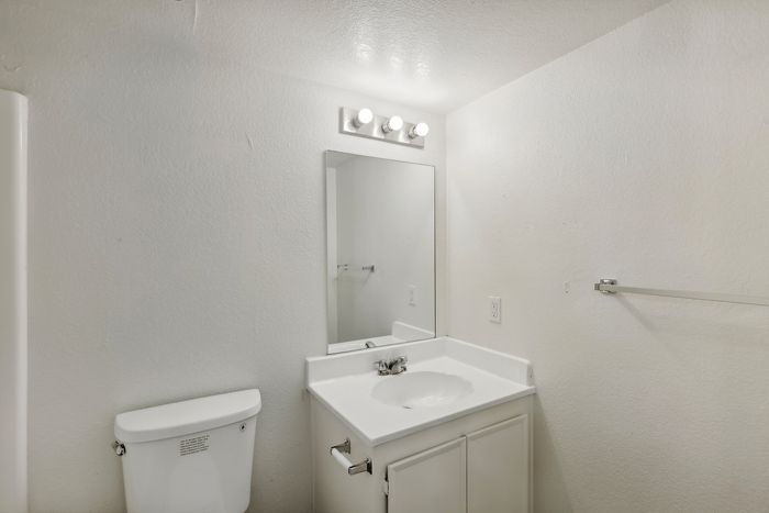 Bright and modern bathroom featuring elegant white decor, a sleek vanity with under-sink storage, and stylish overhead lighting.