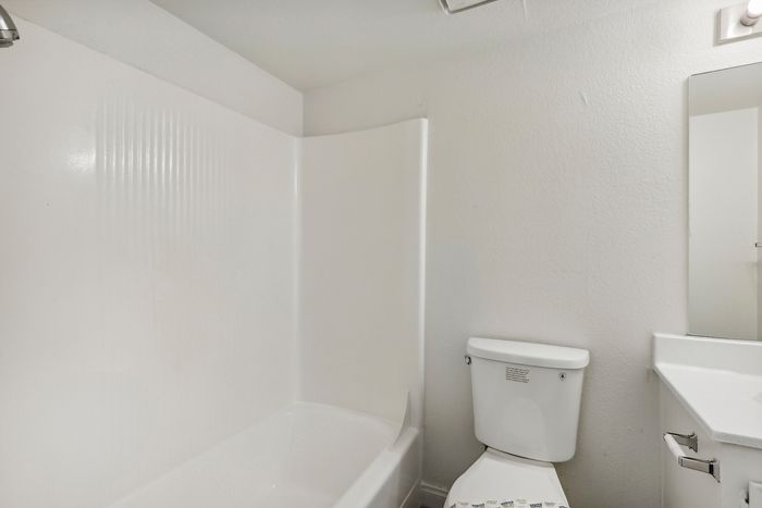 Bright, modern bathroom with a sleek bathtub, pristine white walls, and a contemporary vanity, offering a serene spa-like ambiance.