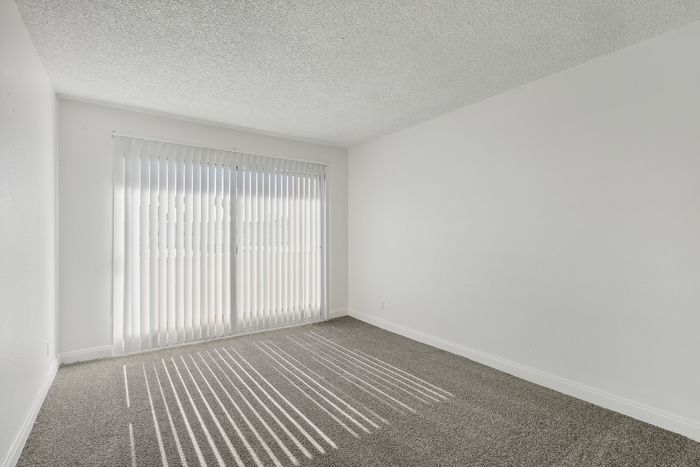 Bright and spacious room with large windows and plush carpeting, perfect for relaxation and comfort.