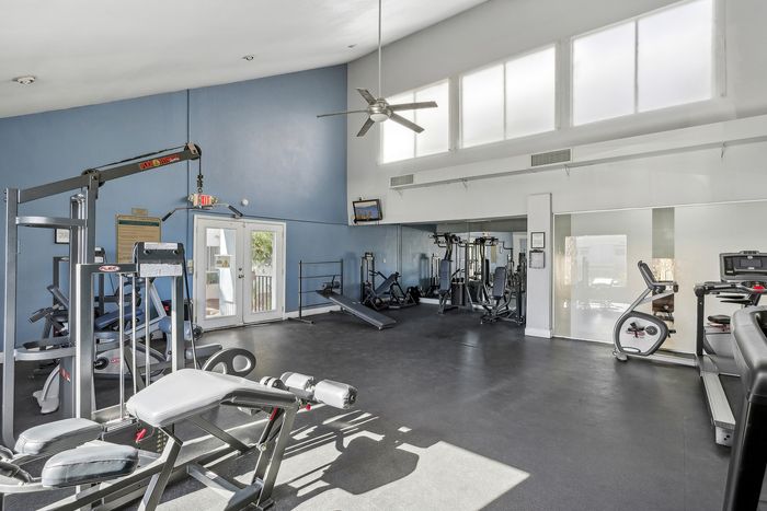 Bright and spacious fitness center with modern gym equipment and large windows for natural light.