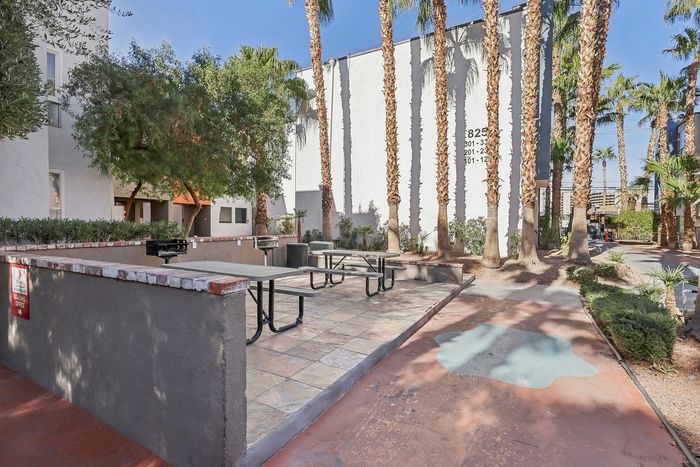 Charming outdoor area with picnic tables, lush greenery, and majestic palm trees, perfect for relaxation and community gatherings.