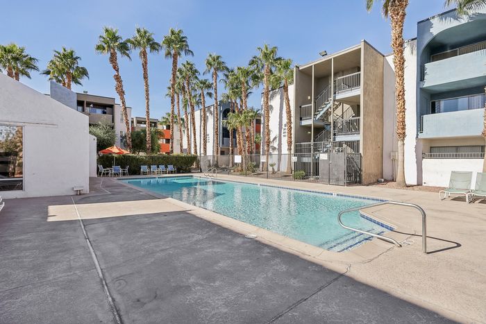 Inviting apartment complex with a sparkling swimming pool, surrounded by palm trees and modern architecture, perfect for relaxation and leisure.