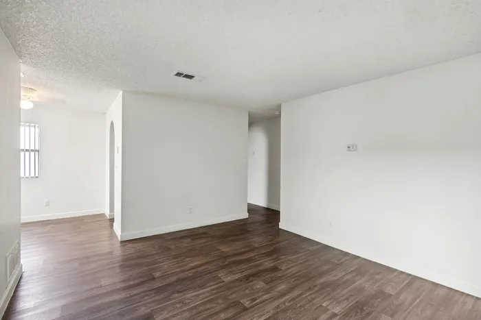 Spacious and bright living area with elegant hardwood floors and fresh white walls, perfect for stylish modern living.