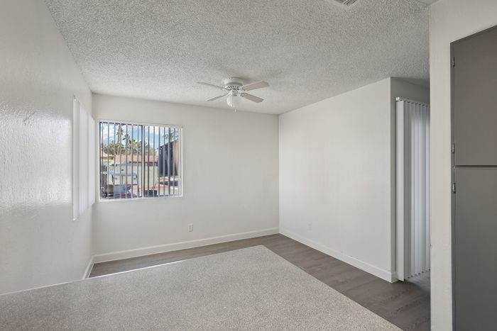 Bright and airy living space with a modern ceiling fan, large window offering natural light, and sleek flooring in a cozy apartment.