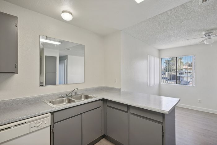 Bright, modern kitchen with sleek countertops, dual sink, and ample natural light from large windows.