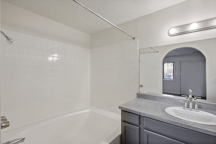 Bright and modern bathroom featuring a sleek vanity, spacious bathtub, and elegant lighting.