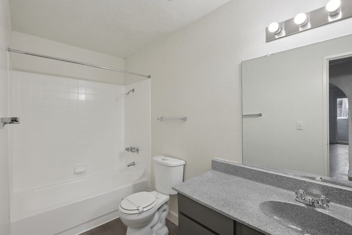Modern bathroom featuring sleek white tile bathtub, elegant vanity, and bright lighting fixtures.