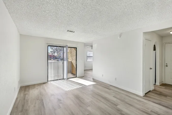 Bright and airy living space with modern wood flooring and large sliding glass doors leading to a charming balcony.