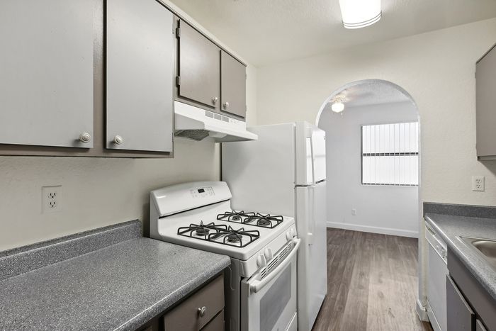 Charming kitchen featuring modern gray cabinetry, sleek countertops, and a white gas stove enhancing the bright, open space.