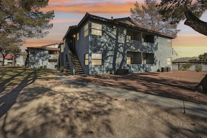 Charming two-story apartment complex with private balconies and scenic views, set against a vibrant sunset sky.
